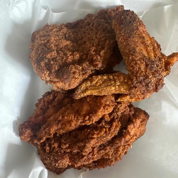 Close-up of crispy, golden-brown Southern fried chicken pieces on white parchment paper.